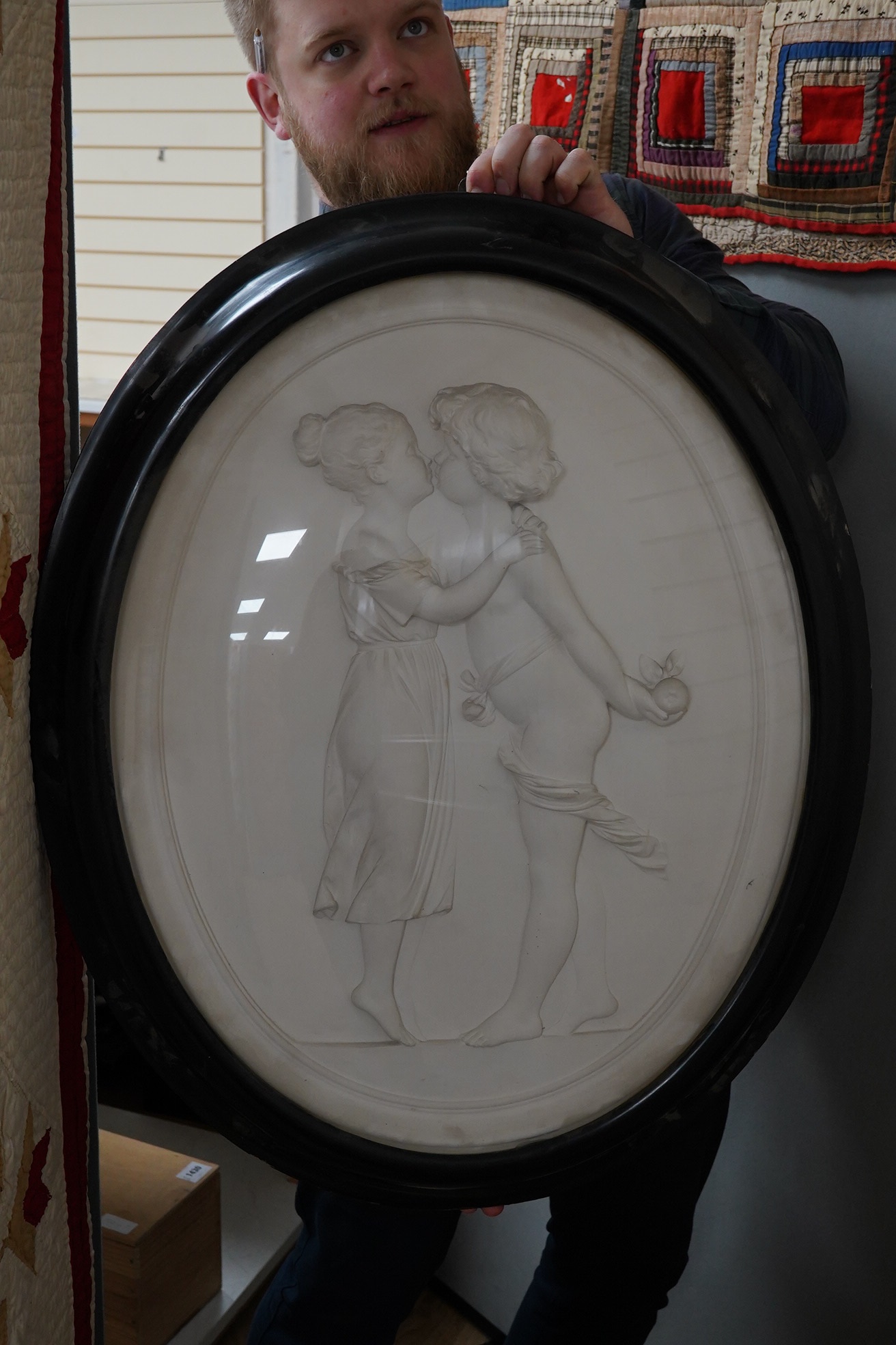 An early 20th century framed oval plaster plaque, classical scene, monogrammed TS, convex glass, 80cm long